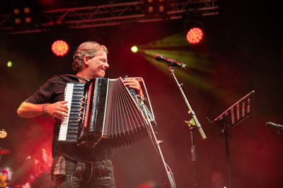 An accordion player - called hubert trenkwalder - and singer on stage at a music festival in tyrol