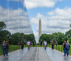 Tourists at park against sky in city