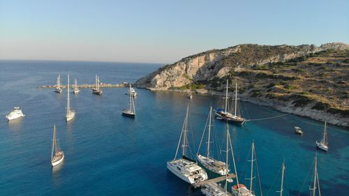 Sailboats moored in sea against clear sky