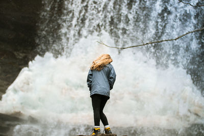 Rear view of woman standing against waterfall