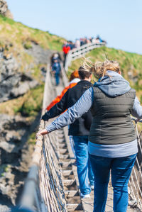 Rear view of people walking on mountain against sky