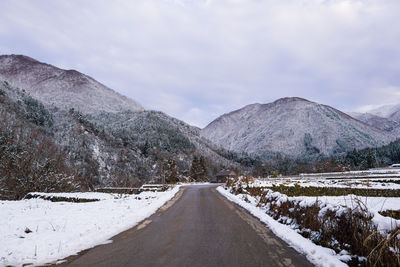 Road leading towards snowcapped mountains against sky