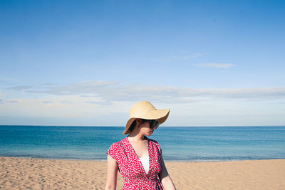 Woman wearing hat at beach against sky
