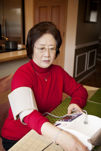 Woman checking blood pressure at home