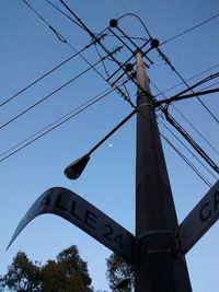 Low angle view of electricity pylon against blue sky