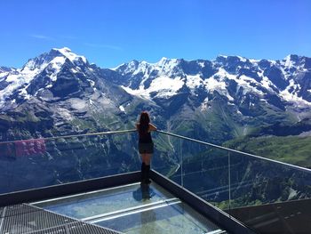 Rear view of person standing on snowcapped mountain against sky