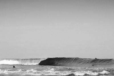 People surfing in sea against clear sky