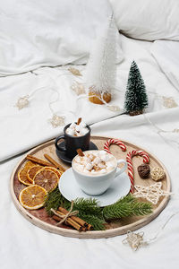Christmas morning coffee cups with marshmallows in bed, candy cane. cozy home, winter holiday mood.