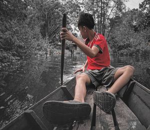 Man sitting on boat against lake