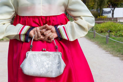 Midsection of woman holding bag standing outdoors