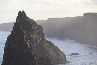 Rock formations in sea against sky