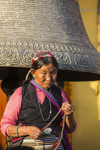 Portrait of woman with arms raised against wall