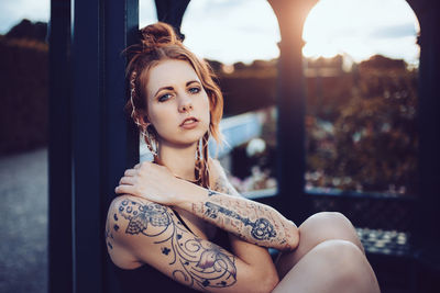 Portrait of beautiful fashion model sitting by column in back yard