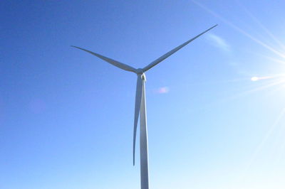 Low angle view of wind turbine against blue sky