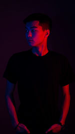 Portrait of young man standing against black background