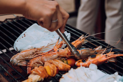 Close-up of man preparing food on barbecue grill