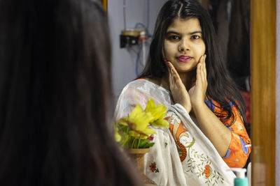 A beautiful indian woman in white saree looking at the camera through mirror with smiling face