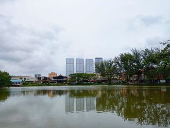 Reflection of trees and buildings in lake against sky