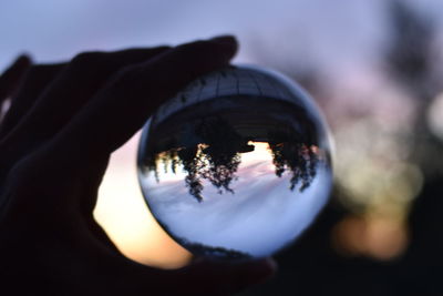 Close-up of hand holding crystal ball with reflection