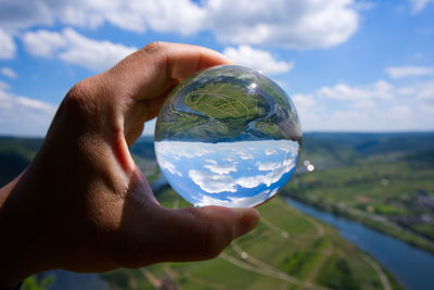 Midsection of person holding glass against sky