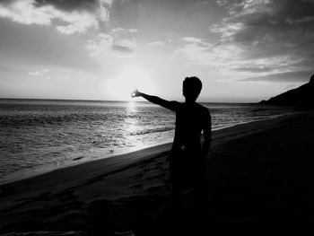 Silhouette man standing on beach against sky during sunset