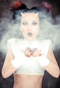 Digital composite image of horned woman blowing powder