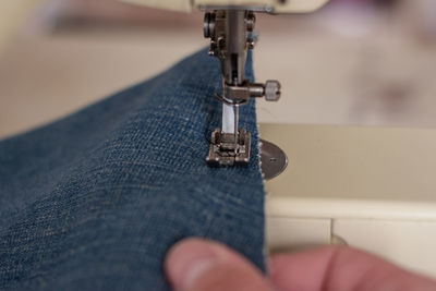 Close up of a person sewing blue jeans on a sewing machine