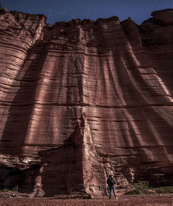 Low angle view of man standing against rock formation against