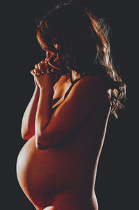 Rear view of shirtless woman against black background