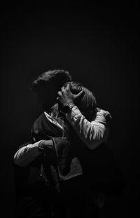 Couple embracing against black background