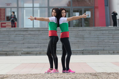 Full length of woman with arms raised standing in city