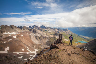 Rear view of man walking on mountain against sky