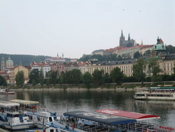 Buildings by river against clear sky