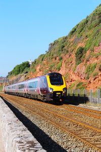 Train on railroad track against clear blue sky