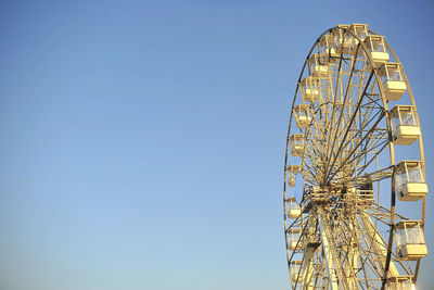 Low angle view of ferris wheel against clear blue sky