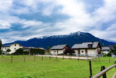 Houses on field by mountains against sky