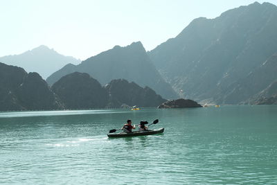 People on boat in lake against mountains