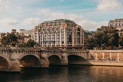 Arch bridge over river against sky in city