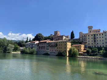 River by buildings against blue sky