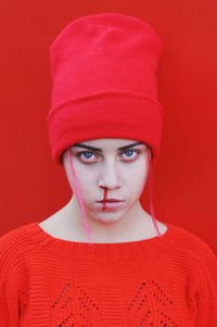 Close-up portrait of young woman against red background