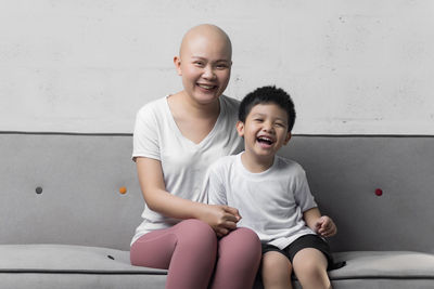 Full length of a smiling boy sitting against wall