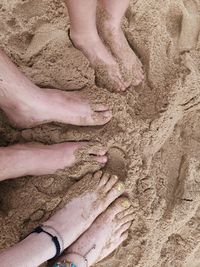 Low section of friends sitting at sandy beach