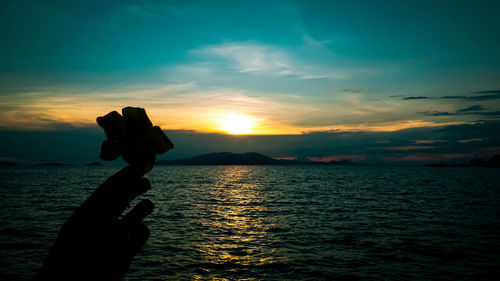 Silhouette person on sea against sky during sunset