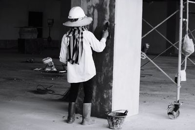 Rear view of man working while standing by wall