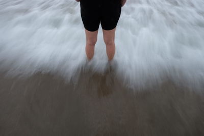 Low section of boy standing on beach