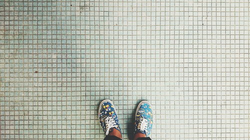 Low section of person standing on tiled floor