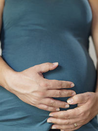 Midsection of pregnant woman holding abdomen