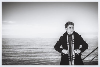 Portrait of young man standing in sea against sky