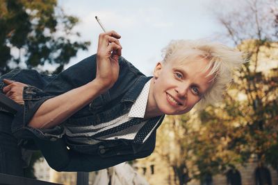 Portrait of smiling young woman holding camera