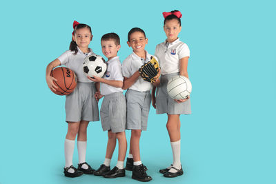 Full length of a boy holding ball against blue background